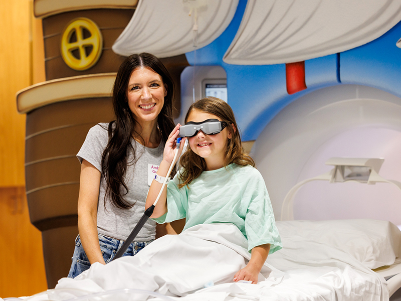 Brittany Farris of Enterprise smiles by daughter Everly, who's wearing a Cinemavision VR headset.